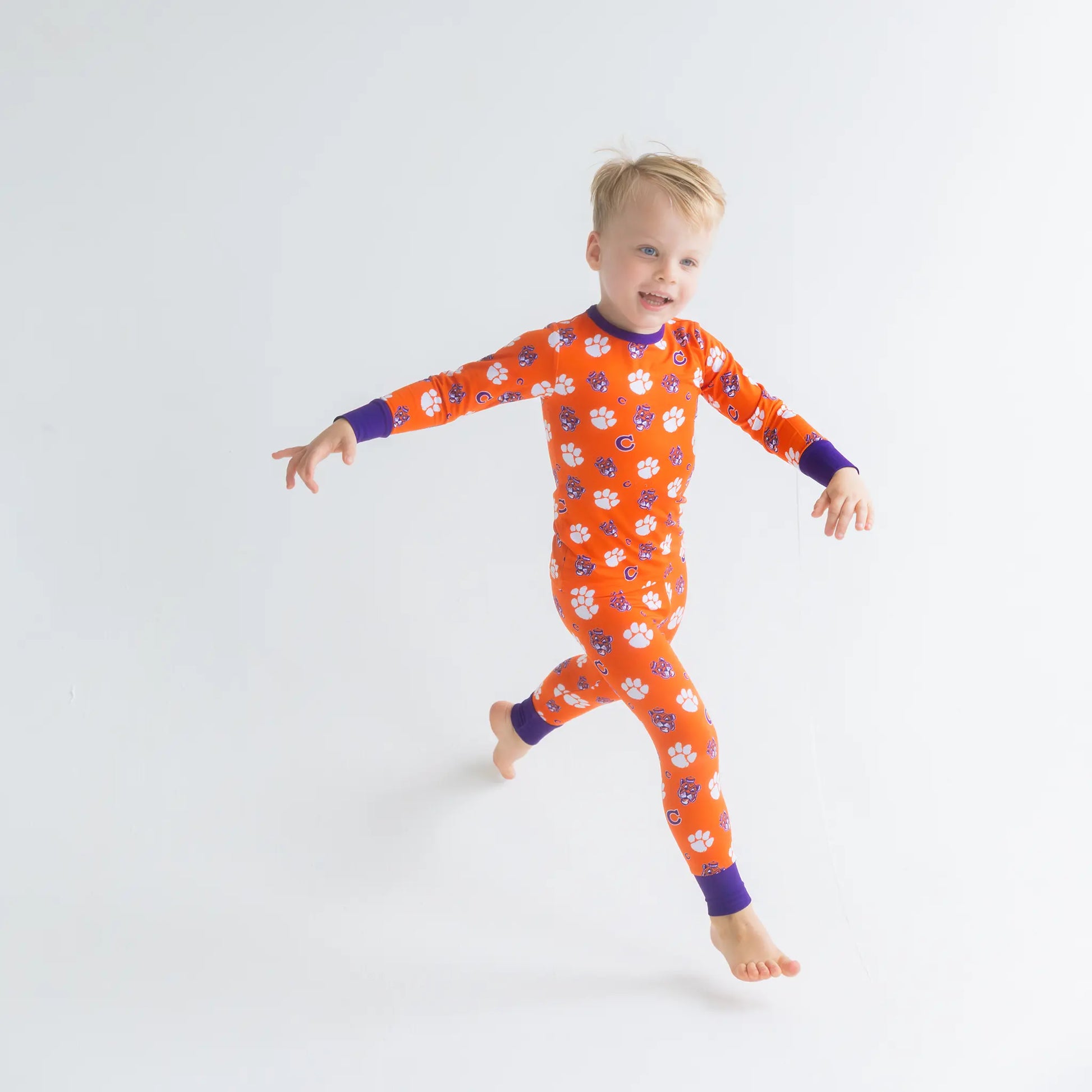 Clemson Tigers Child wearing an orange Onesie with paw prints on a white background made from bamboo.