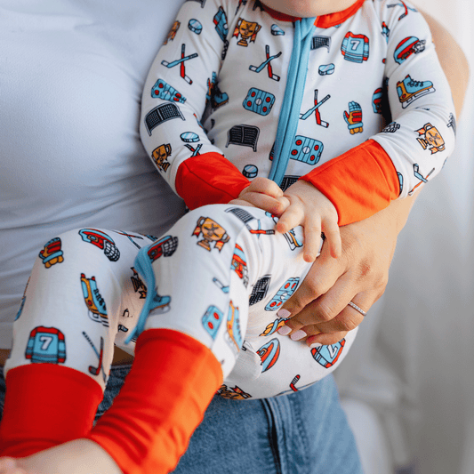 Hockey-themed baby one-piece with soft bamboo fabric, double zippers for easy changes, and a sporty design for little fans.