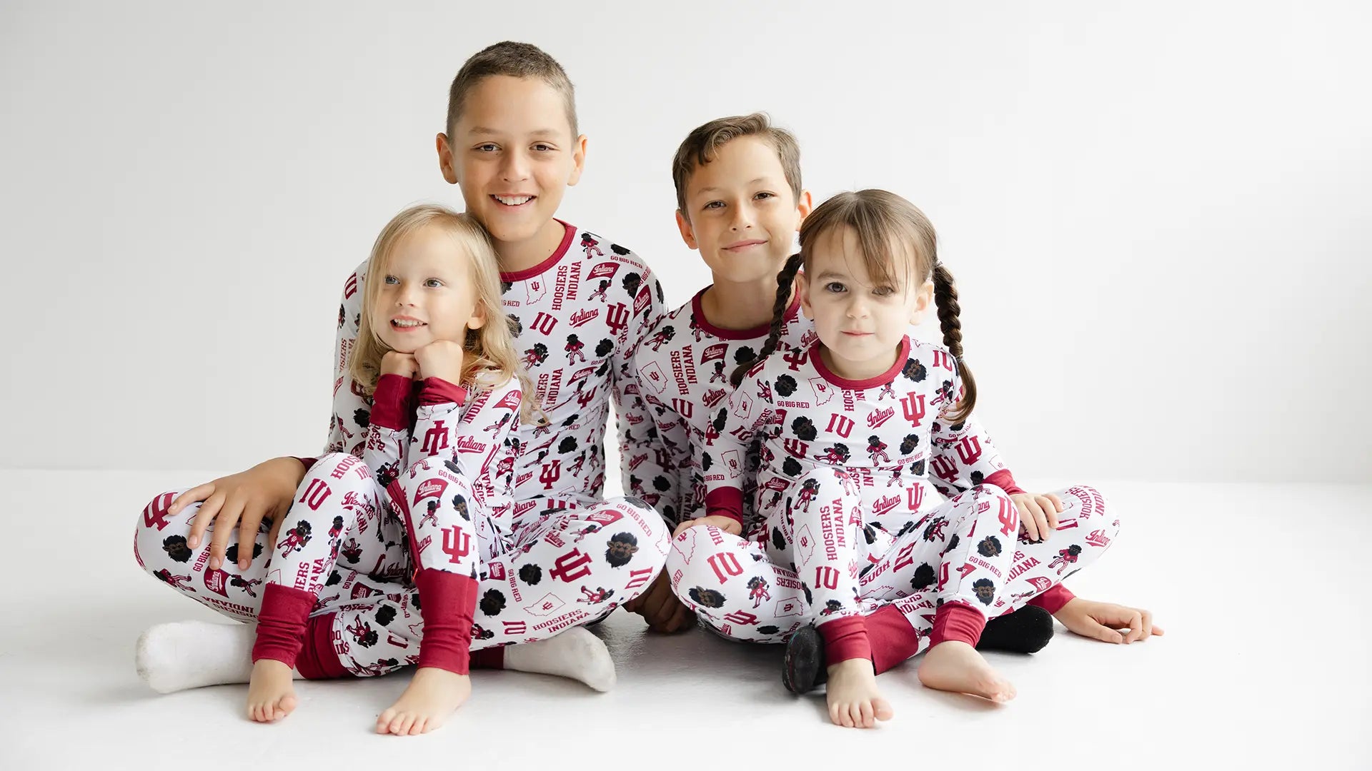 Four children wearing matching indiana hoosiers pajamas on a white background