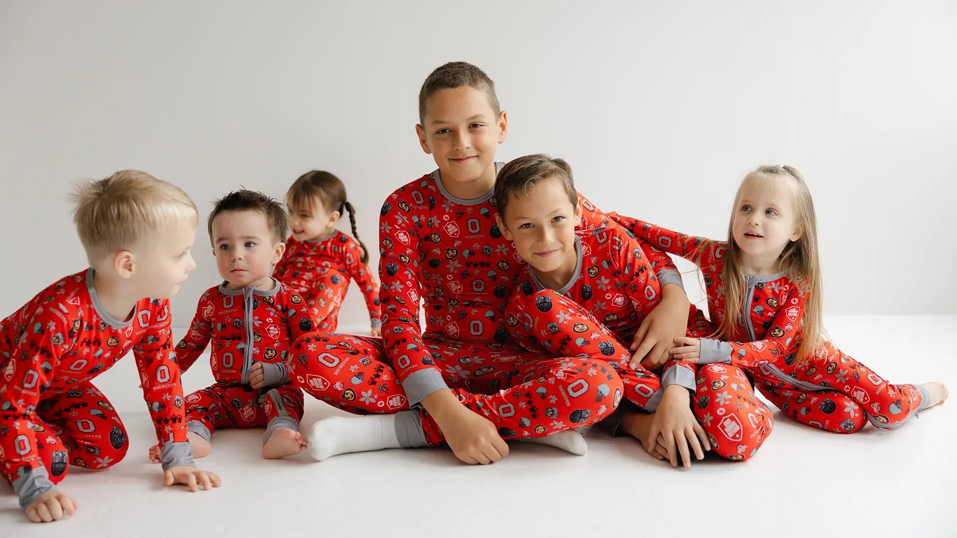 Children wearing ohio state buckeyes red pajamas with a pattern on a white background
