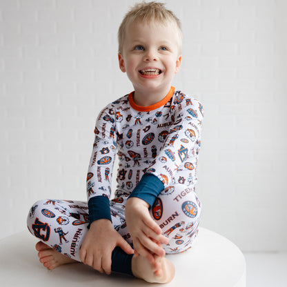 Child wearing a patterned auburn tigers pajama set with visible branding on a white background