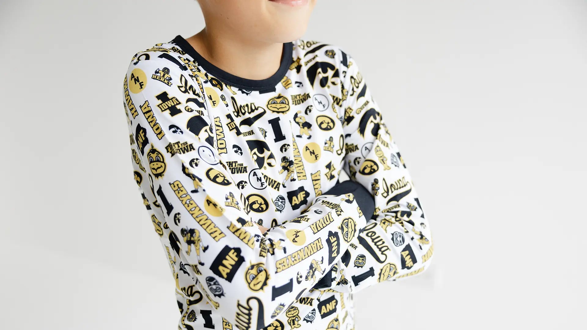 Child wearing a pajama set with black and gold iowa hawkeyes officially licensed print