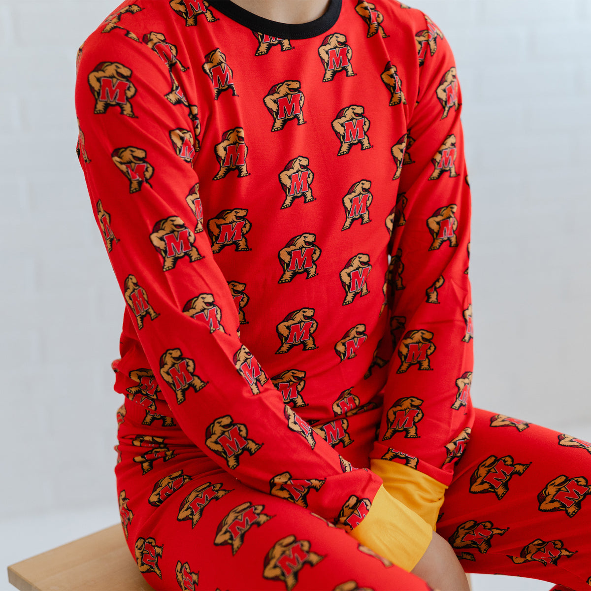 A youth wearing a red long-sleeve pajama top and matching pants with an allover Maryland terrapins Testudo  print.