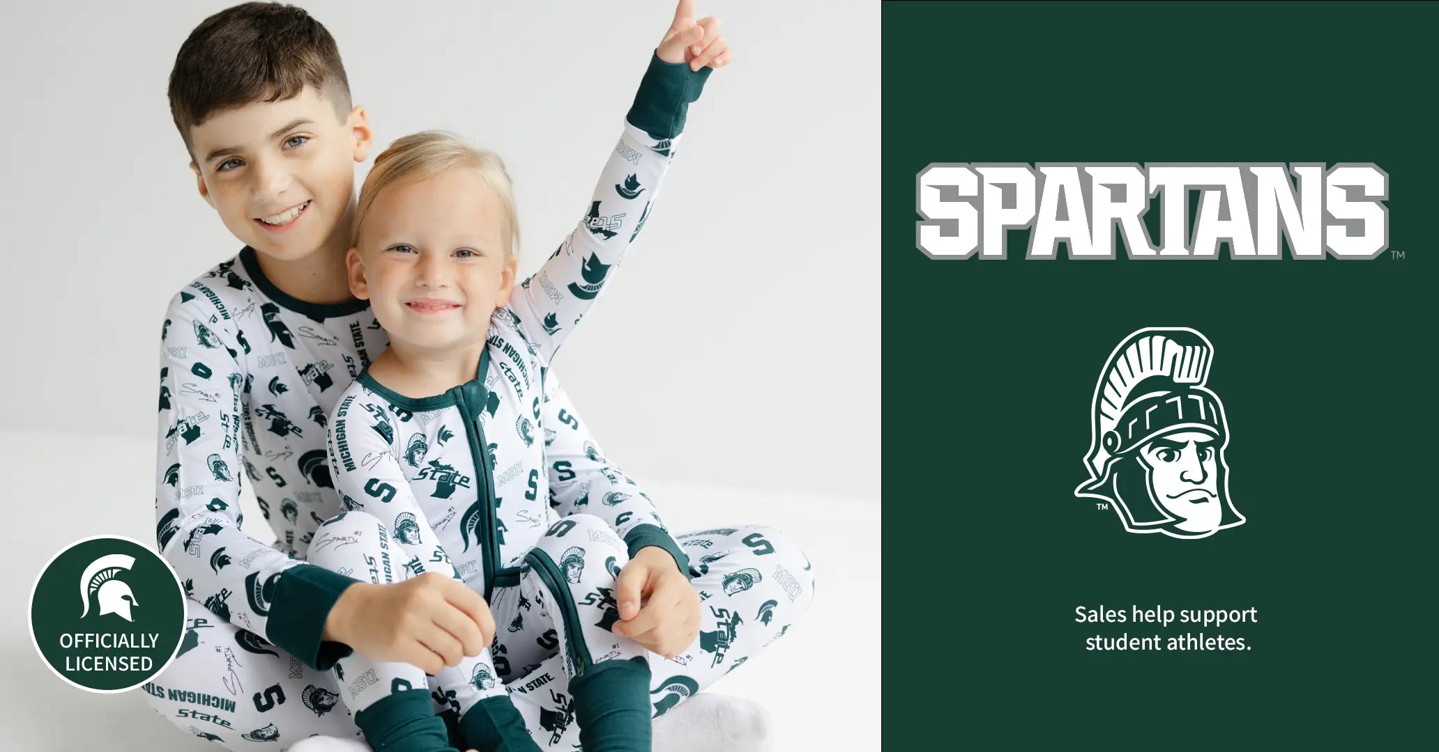 Two children wearing Michigan State University-themed pajamas with a Spartans logo on the right.