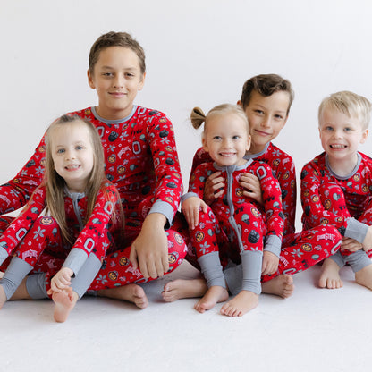Five children sitting together wearing matching scarlet officially licensed ohio state buckeyes pajamas with gray cuffs and legs, photographed against a plain light background.