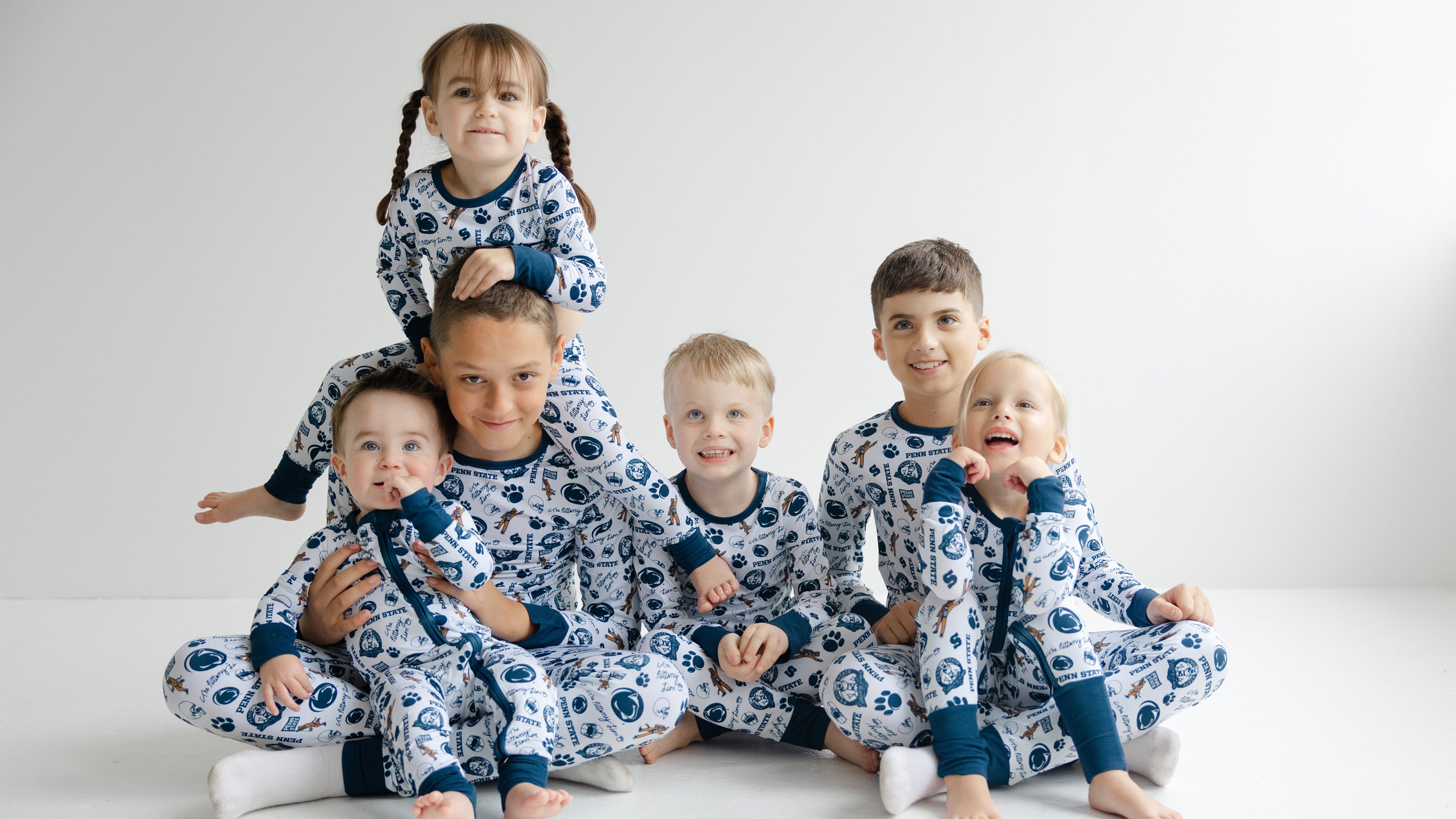 Six children wearing matching penn state nittany lions bamboo patterned pajamas, posed together on a clean white studio background.