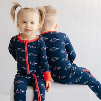 Two children wearing matching navy UTSA roadrunners bamboo zipper one piece sleeper.