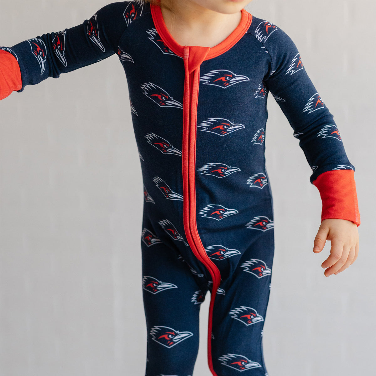 A baby wearing a navy UTSA roadrunners bamboo zipper one piece sleeper.