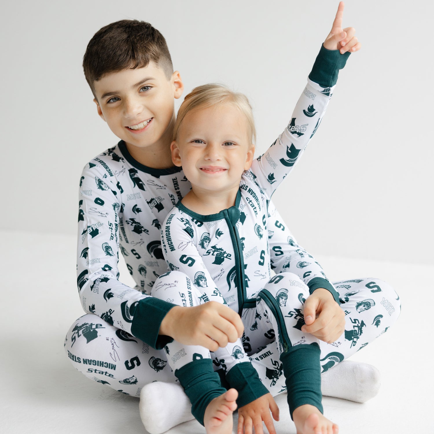 Michigan State Spartans newborn bamboo sleeper in white with green trim and team logo details.